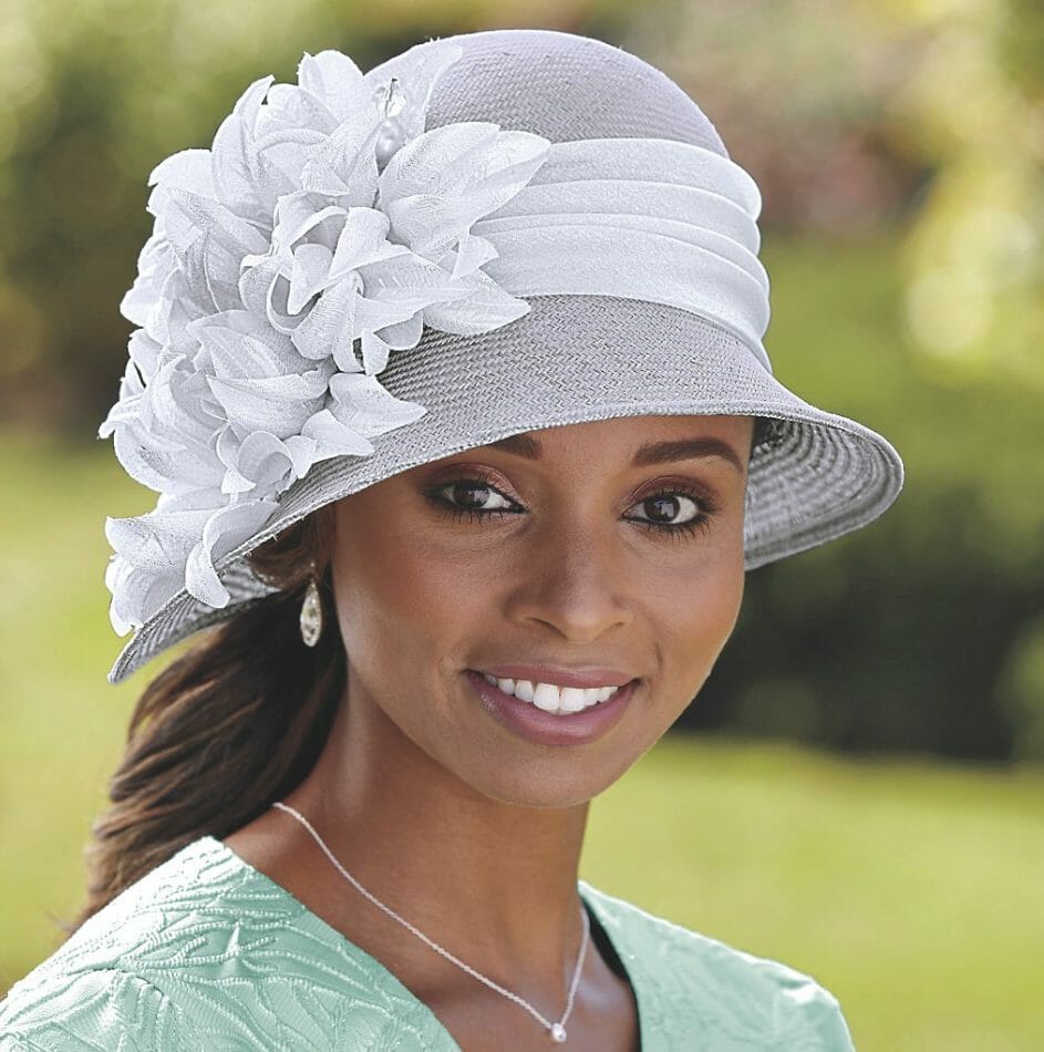 Black woman wearing gray hat with white flower ribbon