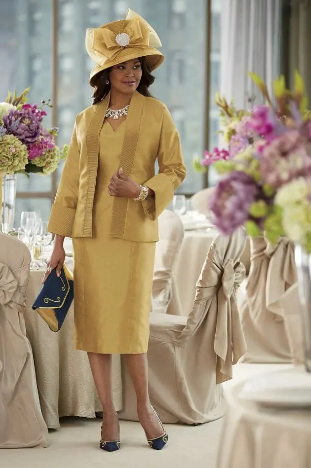 Black woman in bronze jacket dress with big bow bronze hat