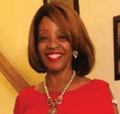 Ashro lookbook customer Cynthia, a smiling black woman with smooth, light brown hair, wearing a flowing red pantsuit.