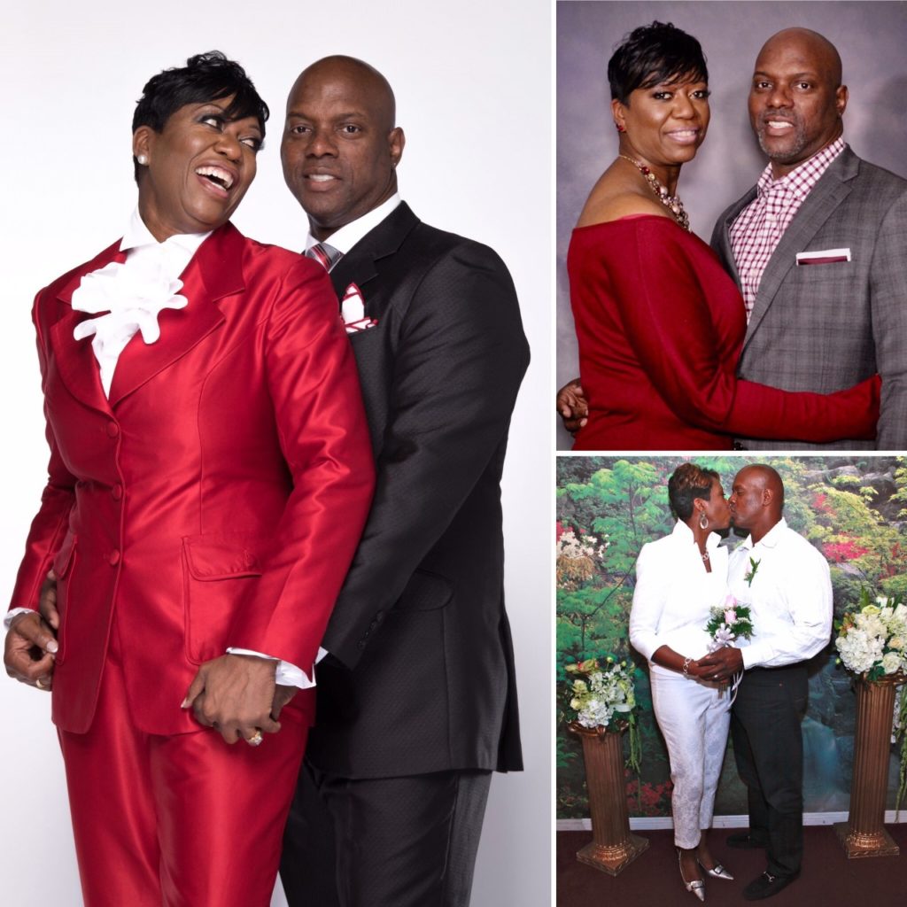 A black couple, with the woman wearing red and the man in a black suit, and kissing in front of greenery.
