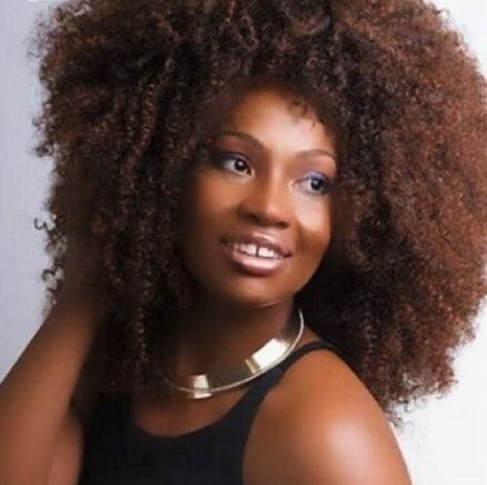 A smiling African-American woman with a big Afro hairstyle, black tank top, and silver necklace.