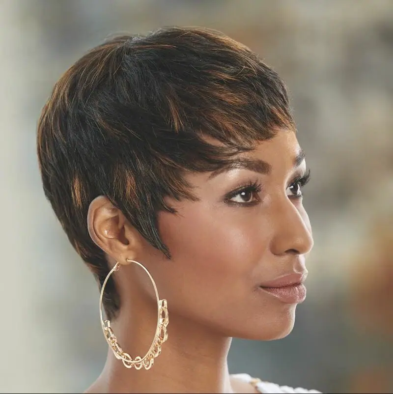 A black woman wearing large gold hoop earrings and a short, layered brown wig with highlights, by Vivica Fox.