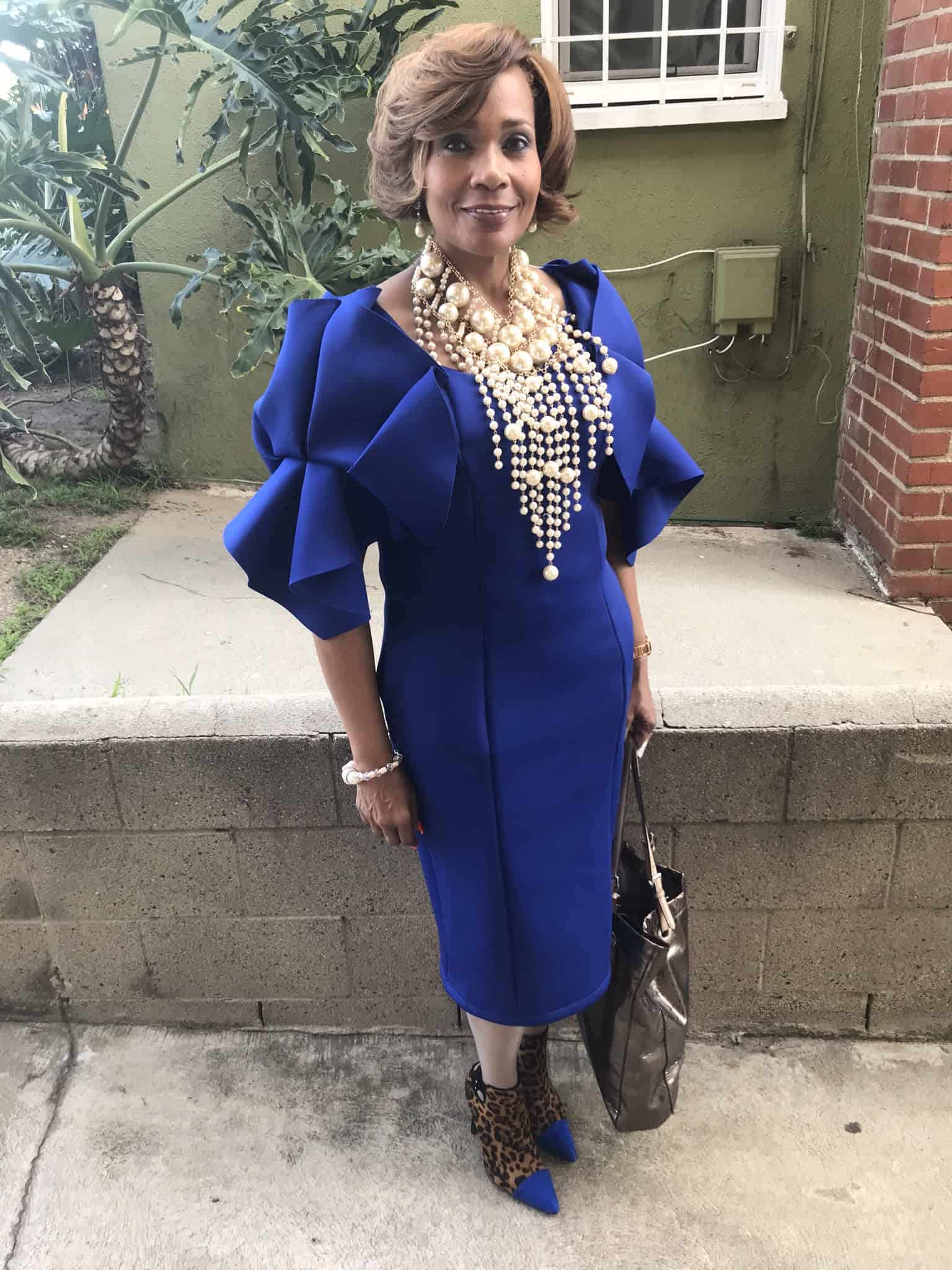 Ashro Woman of the Week, Dr. Angela, a smiling black woman in a blue dress with a long silver bib necklace.