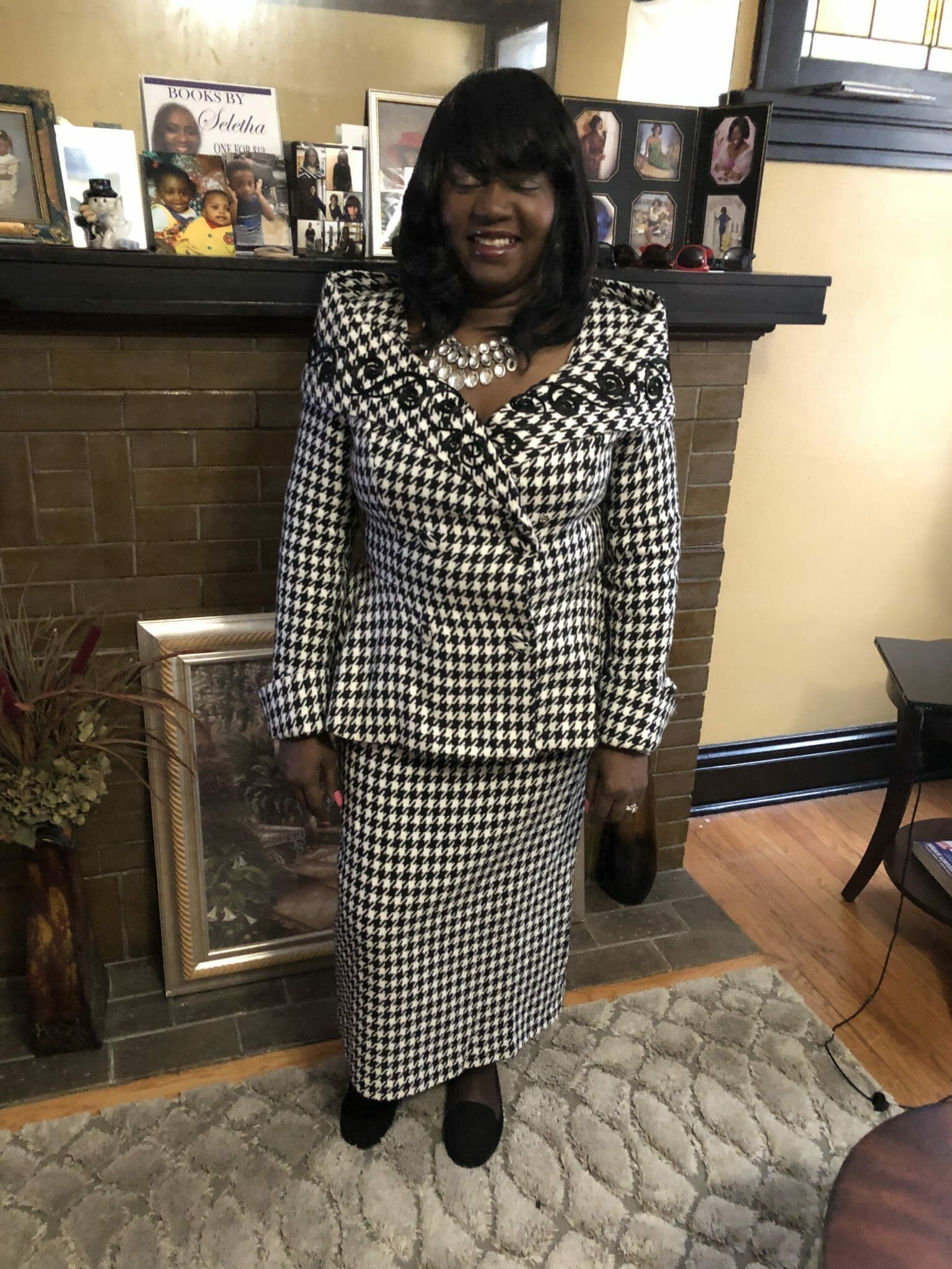 Ashro Woman of the Week, Seletha, a smiling black woman wearing a black and white checked suit with skirt.