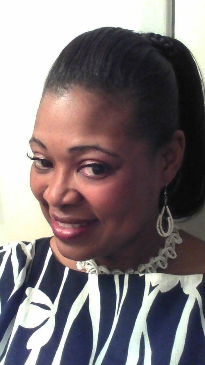 Ashro Woman of the Week, Janice, a black woman with hair pulled back, wearing a black and white print dress.
