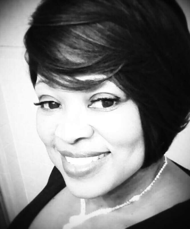 Ashro Woman of the Week, Janice, a smiling black woman with short hair and smooth bangs, wearing a necklace.