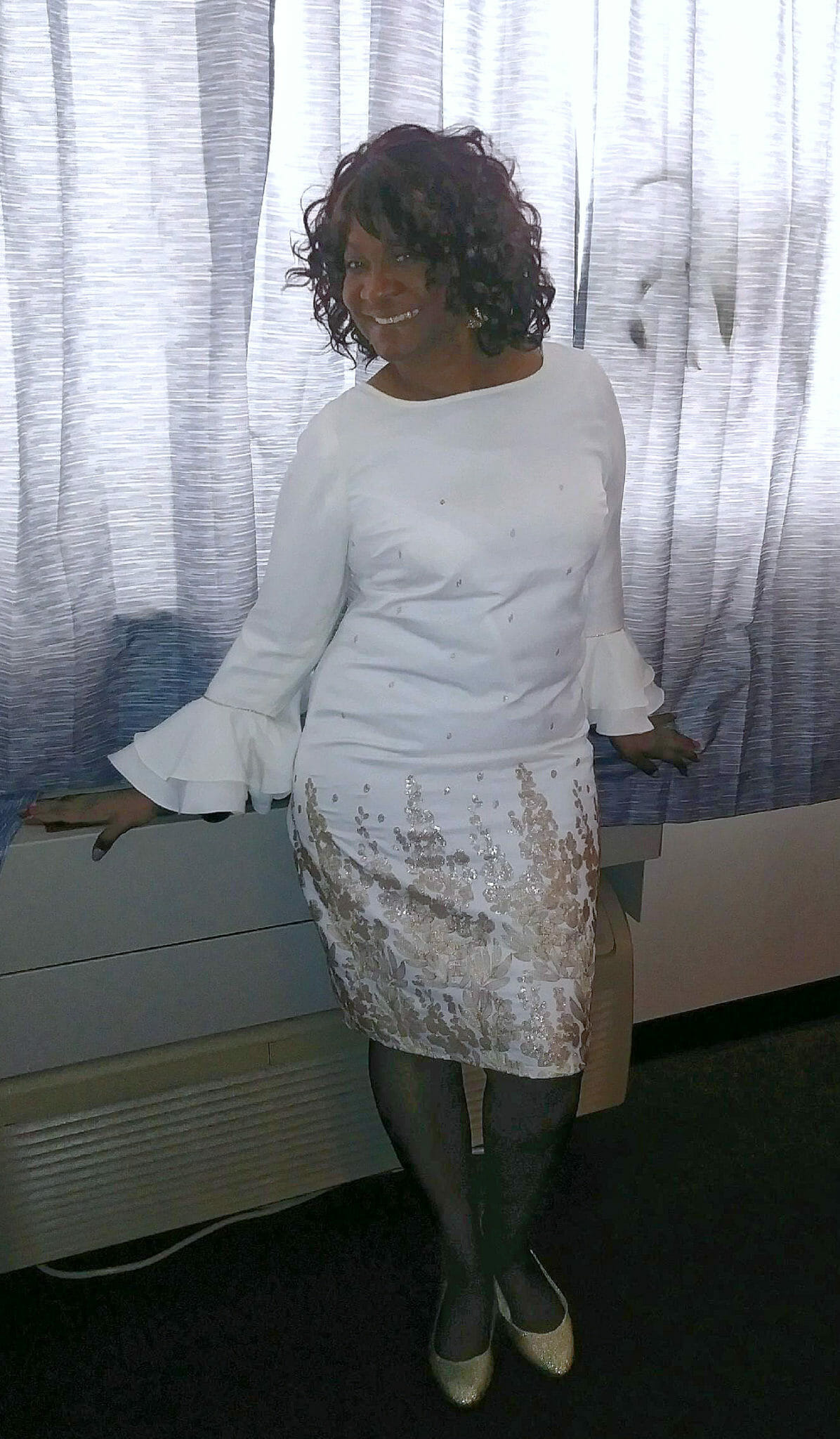 Ashro Woman of the Week MARY, an African-American woman wearing a white dress, posed by a curtained window.