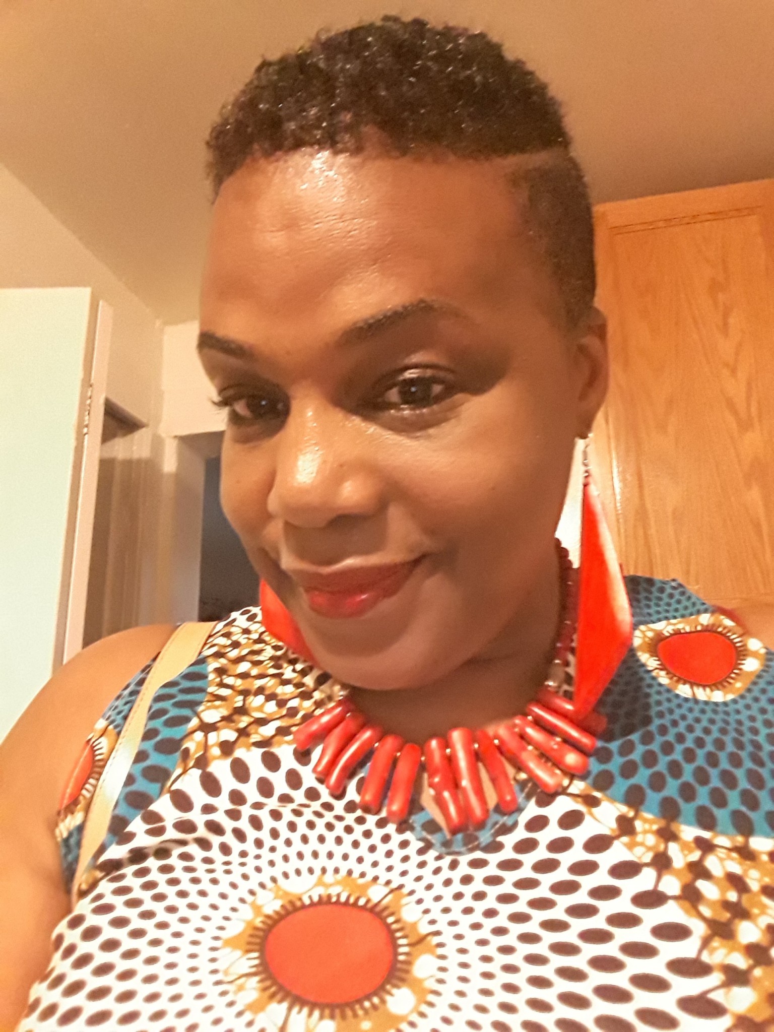 Ashro Woman of the Week MICHELLE, a black woman with short hair, wearing a red necklace and drop earrings.