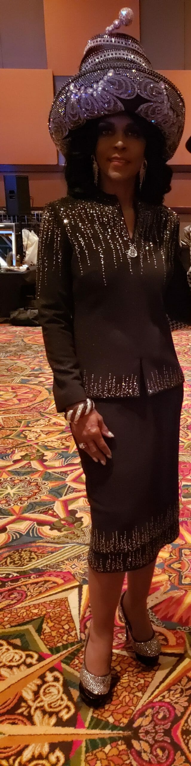Ashro Woman of the Week Brenda, a smiling African-American woman wearing a black dress and a black hat.