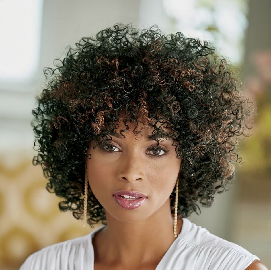 Black woman wearing a white top and a curly wig