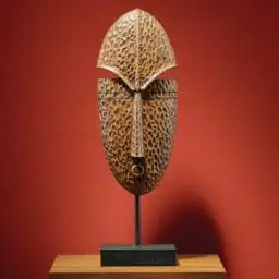 Tabletop Carved Face Décor on side table against red wall