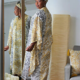 Woman posing in front of mirror wearing head wrap and dress