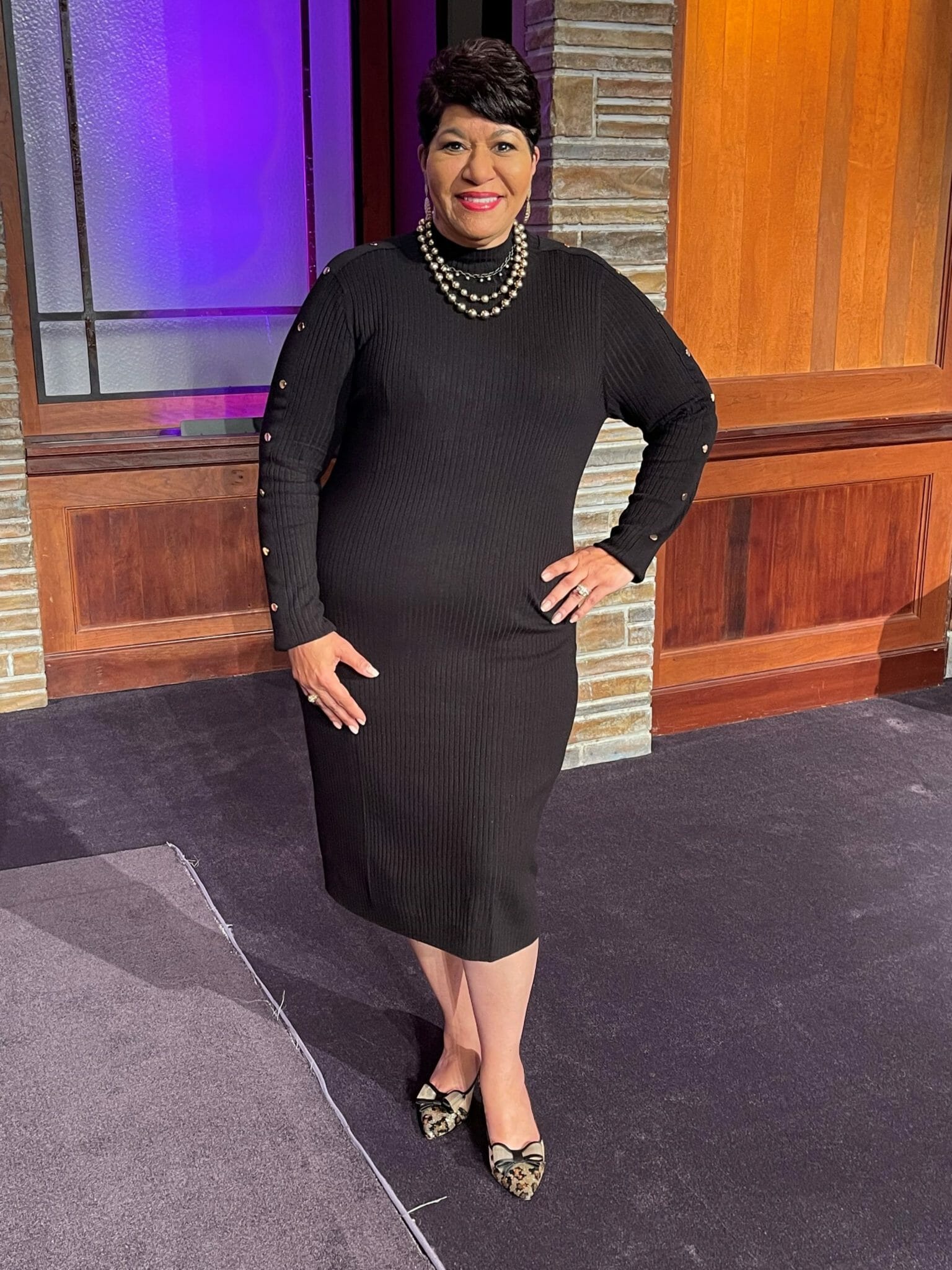 Ashro customer wearing black two piece dress posing on a stage