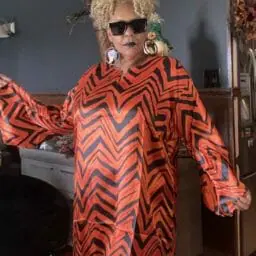 Woman posing in a orange and black pattern caftan