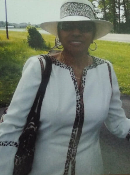 Closeup of a woman in a hat and white outfit.