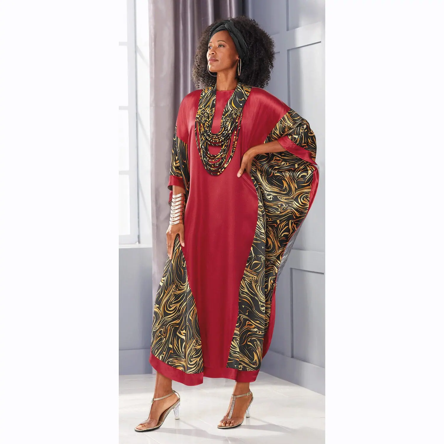 Black female model wearing a headwrap, caftan and heels.