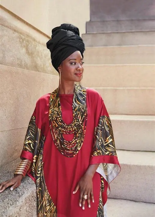 Sarah Paul modeling a black headwrap and red caftan