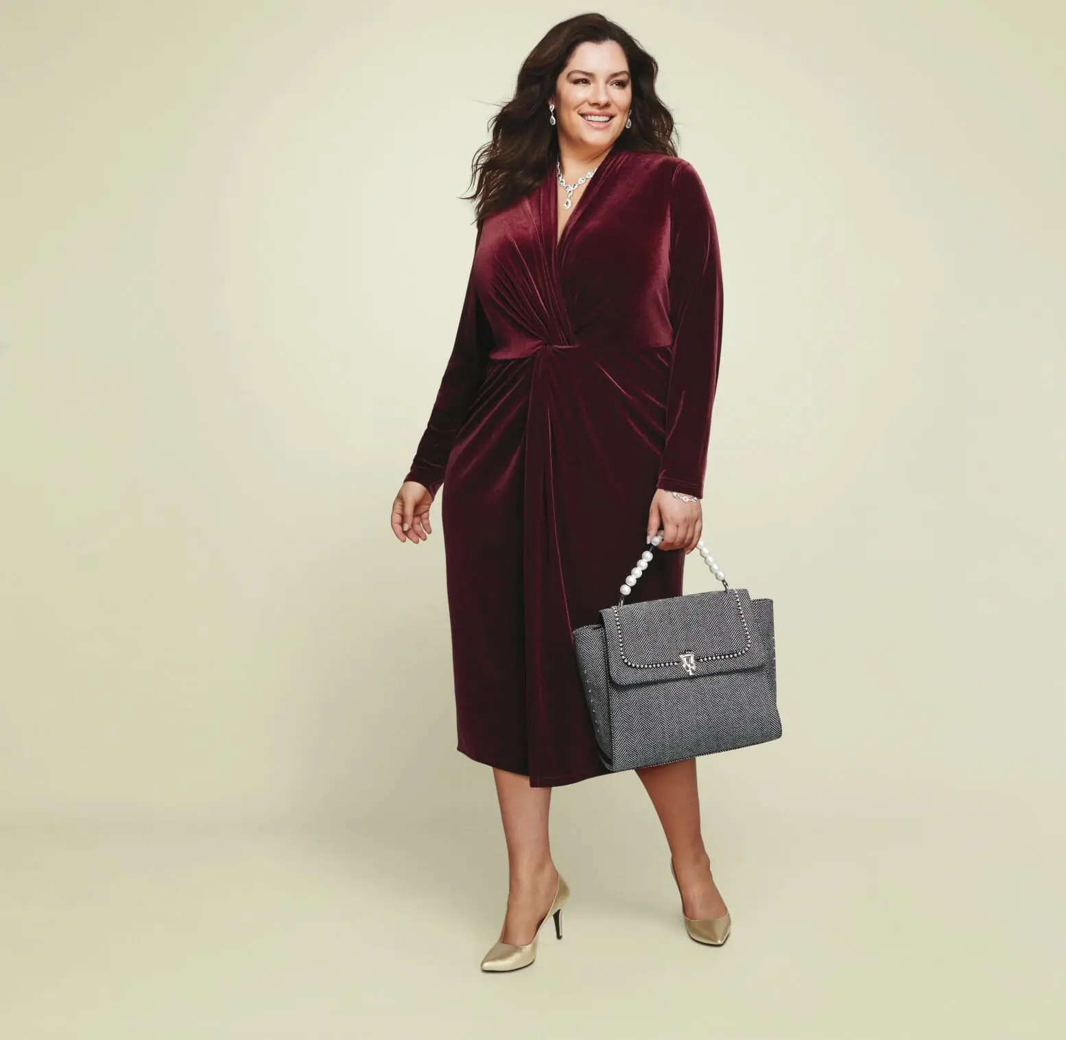 plus size model wearing a burgundy long-sleeve dress with gold metallic heels.