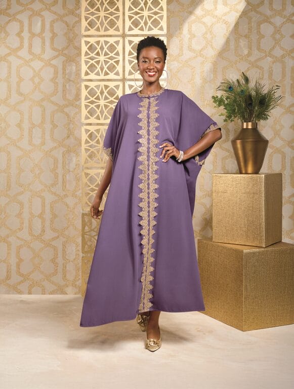 Woman in purple kaftan with gold trim, standing in a room with gold geometric wallpaper.