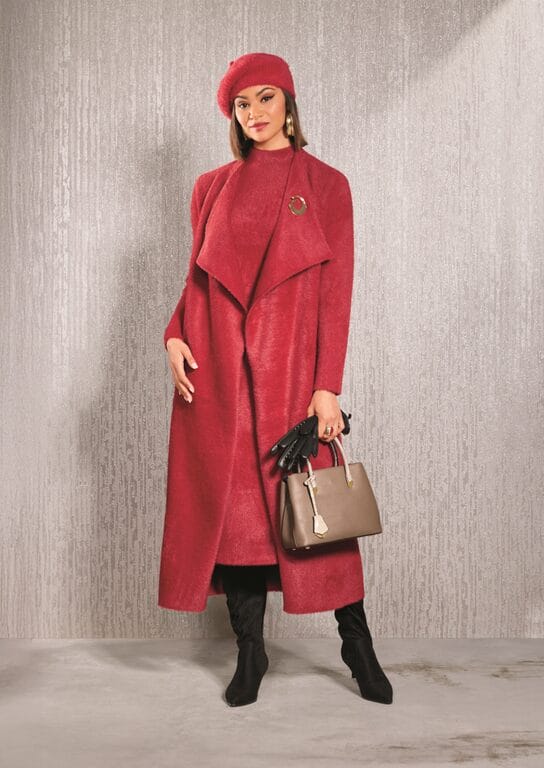 Woman in red coat, beret, and boots holding a taupe handbag.