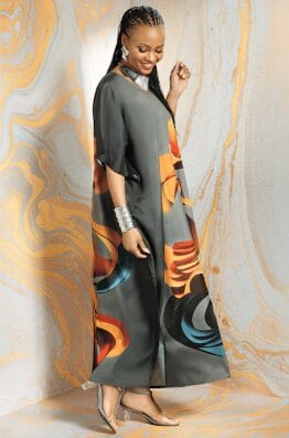 Woman in a flowing gray dress with abstract colorful print, silver bracelet, and clear heels.