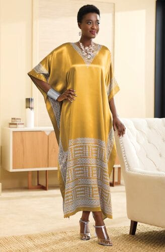 Woman in a golden kaftan with geometric trim, silver jewelry, and clear heels.