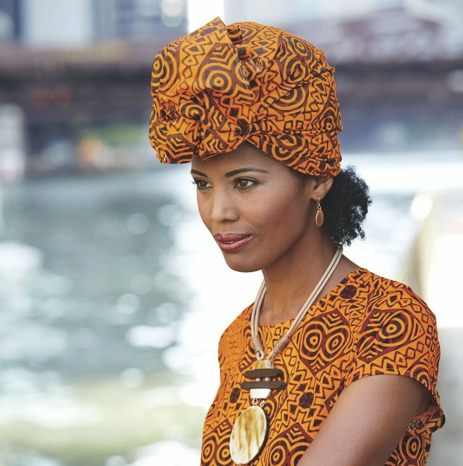 Black woman wearing orange and black geometric print headwrap
