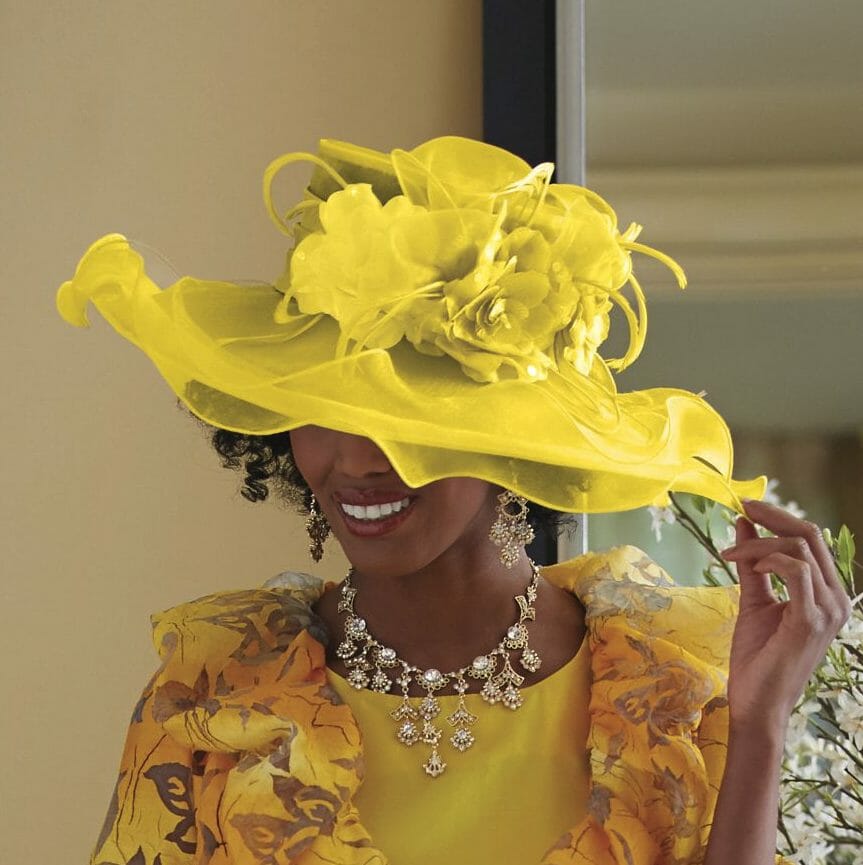 African-American woman wearing big yellow mesh overlay with flower hat