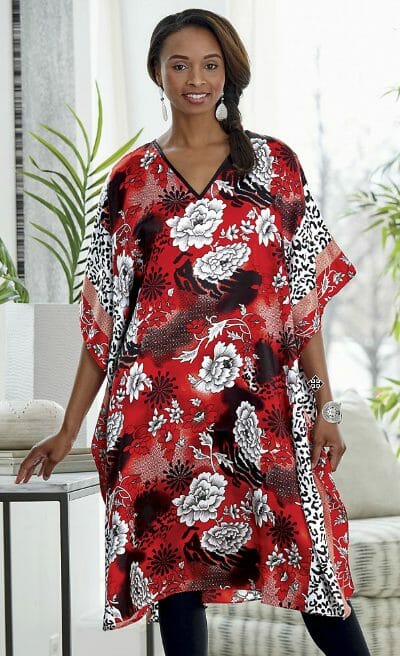 An African-American woman wearing a short red, white, and black floral print caftan and black leggings.