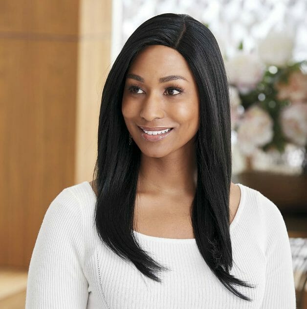 An African-American woman wearing long, black straight wig with a side part.
