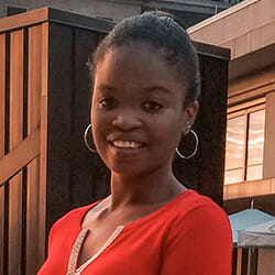 Tabitha, a smiling young African-American woman with her hair in a bun, wearing a bright red top.