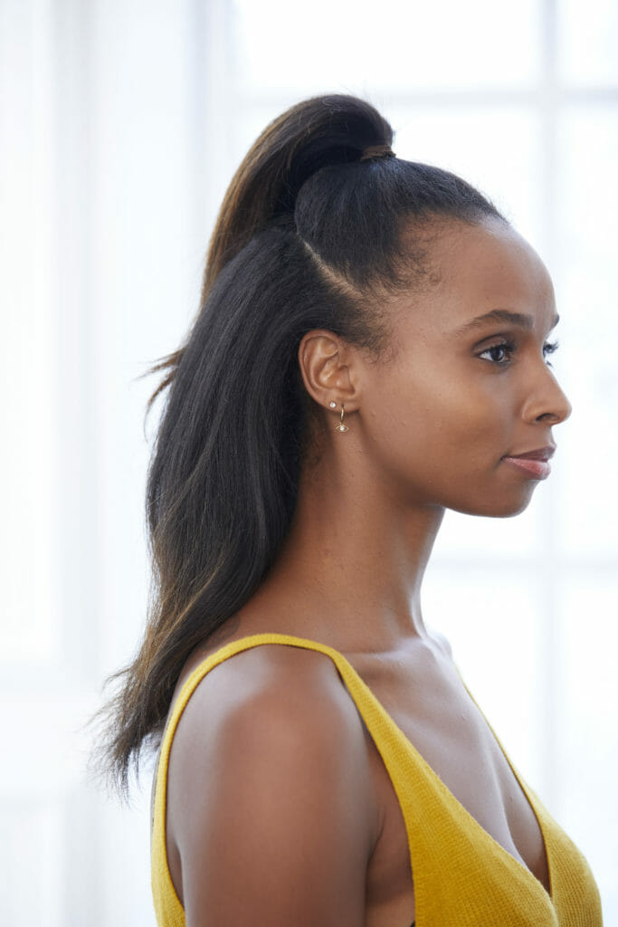 A black woman with the top of her hair in a small ponytail at the top of her head.