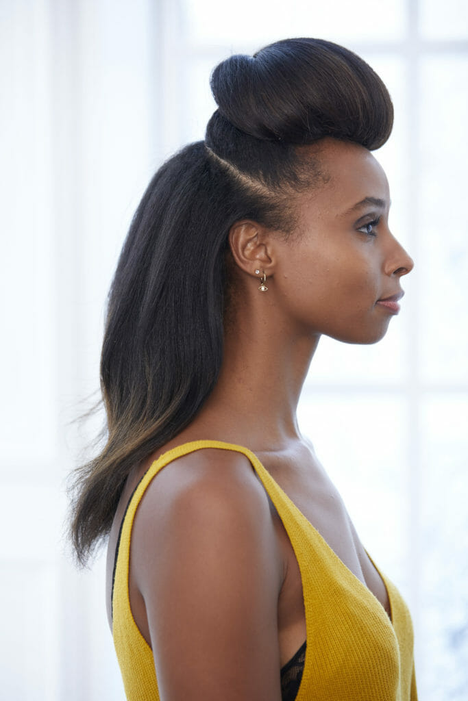 A black woman with Pompadour hairstyle, long hair at back, before French twist is finished.