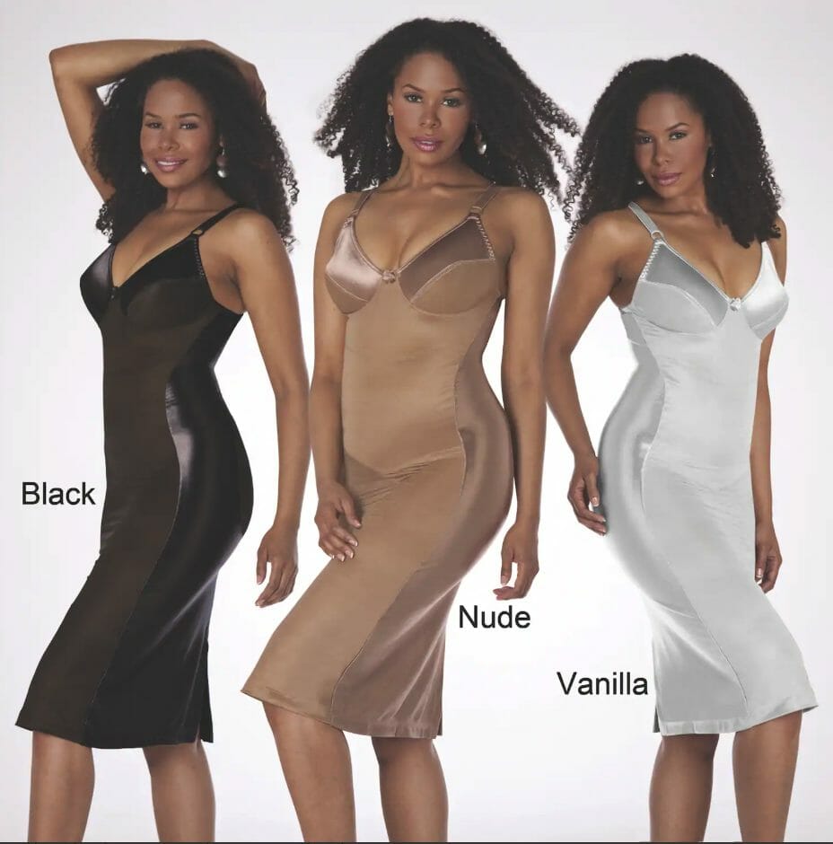 An African-American woman with long hair wearing black, nude and white versions of a slip bodyshaper.
