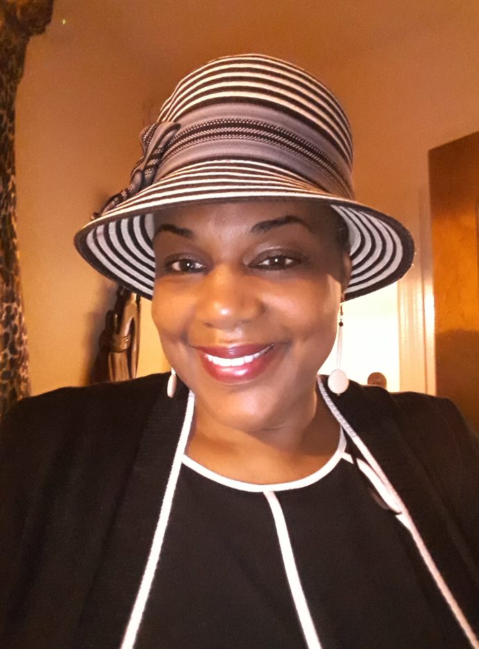 Ashro Woman of the Week MICHELLE B., wearing a black jacket dress with white trim and a summery hat.