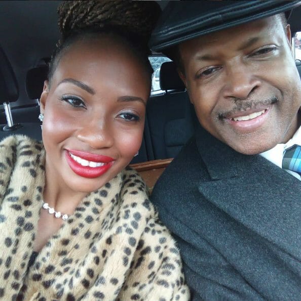 A smiling African-American couple wearing dress clothes, in a vehicle.