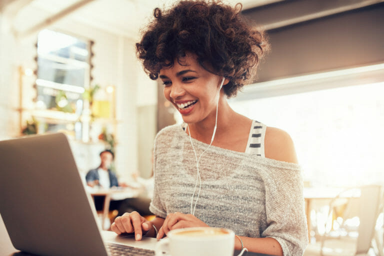Happy, young African-American woman with short curly brown hair, working on a laptop.