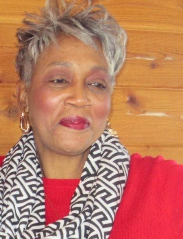 Ashro Woman of the Week, Brenda, a black woman with short silver hair in red dress with a black and white scarf.