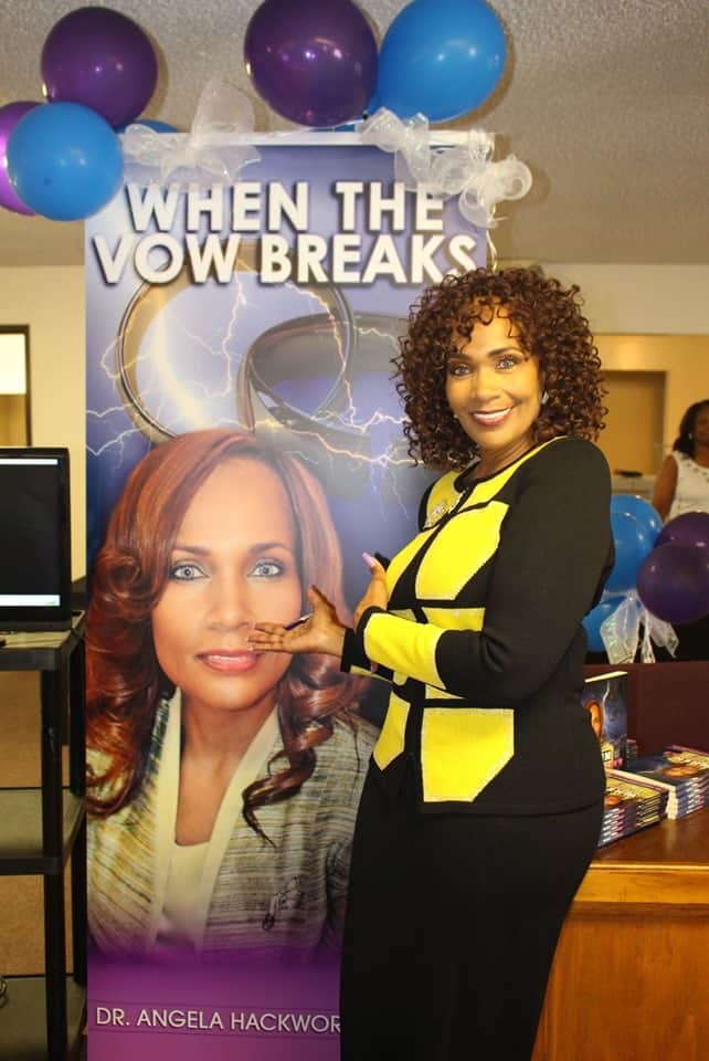 Ashro Woman of the Week, Dr. Angela, a smiling black woman with curly brown hair, wearing a yellow and black suit.