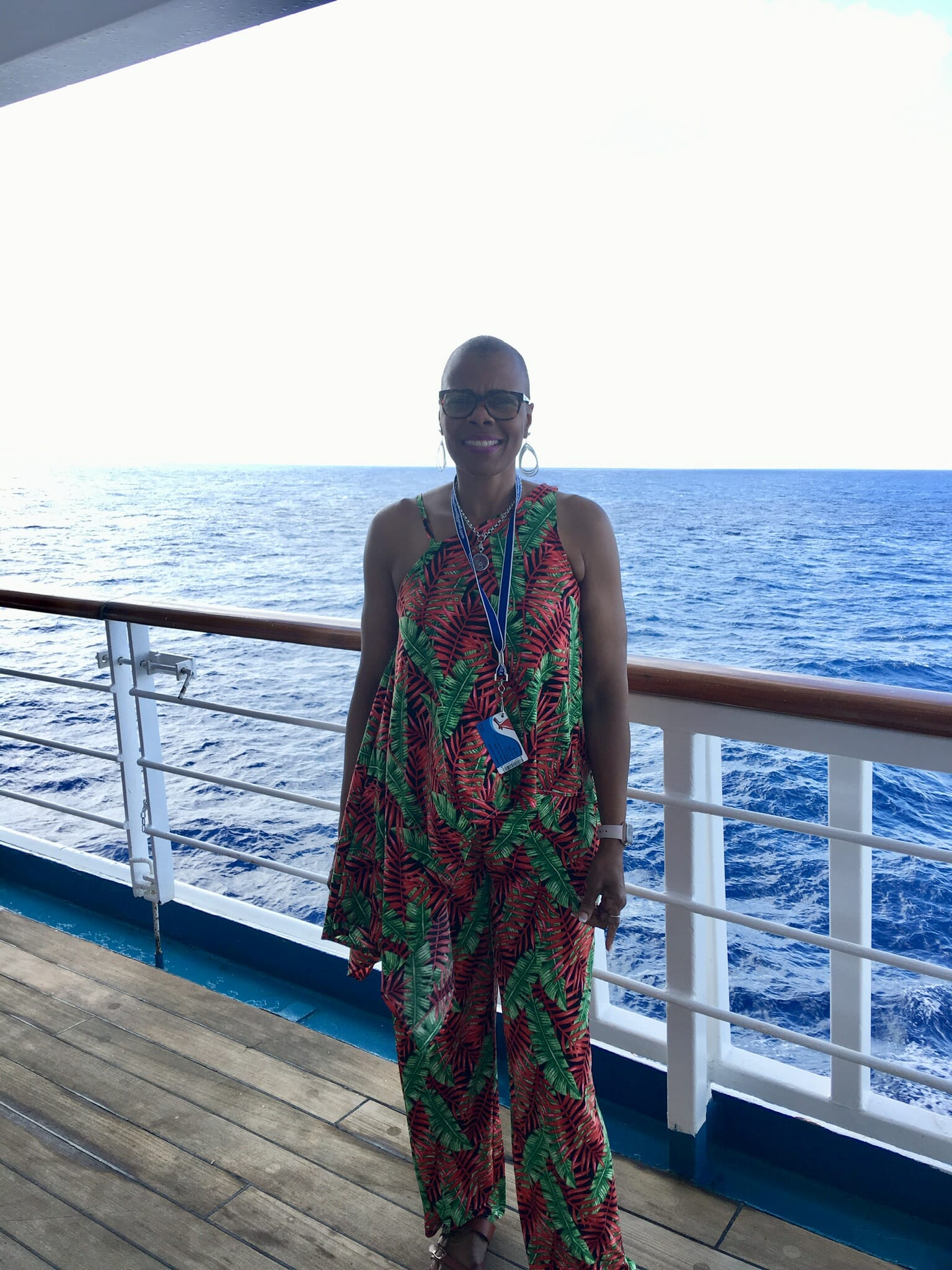 Ashro Woman of the Week, Carolyn, an African-American woman wearing a colorful pant set on the deck of a ship.