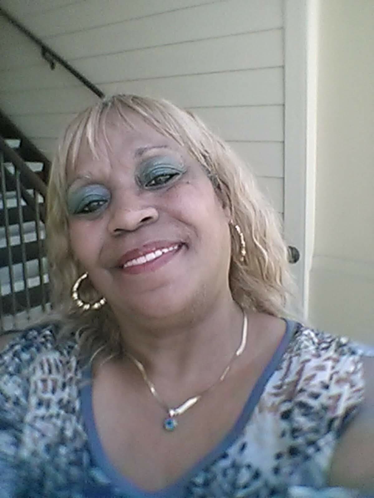 Ashro Woman of the Week, Tracey, a smiling African-American woman with blonde hair and bangs, in a print top.