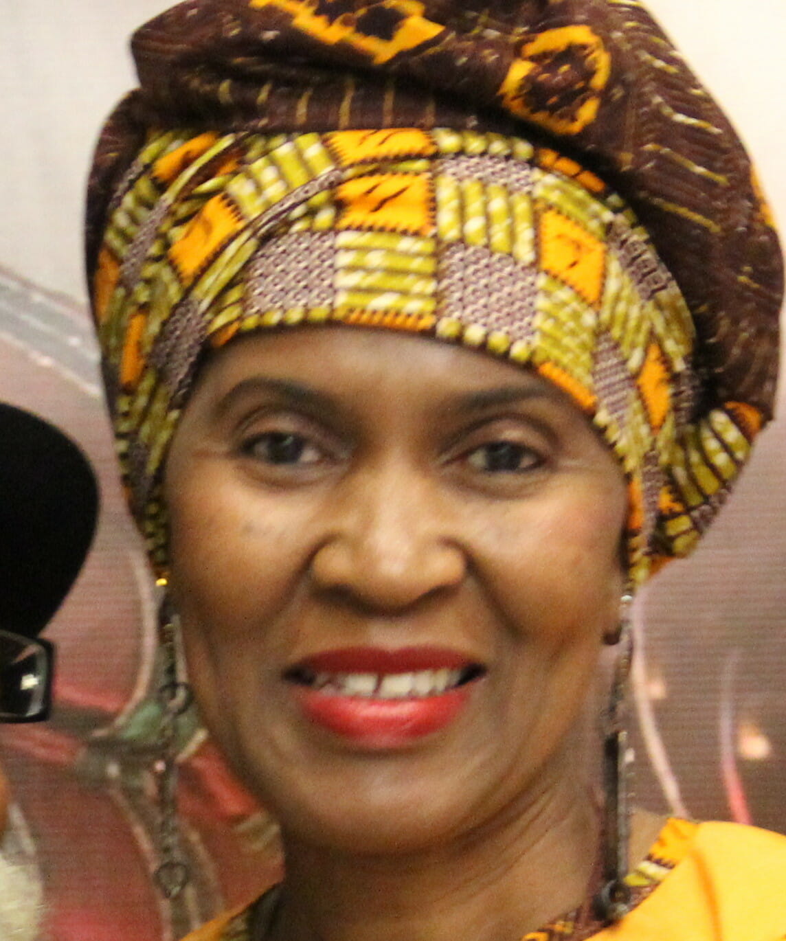 Ashro Woman of the Week, Wajeedah, a smiling African-American woman wearing a yellow print headwrap.