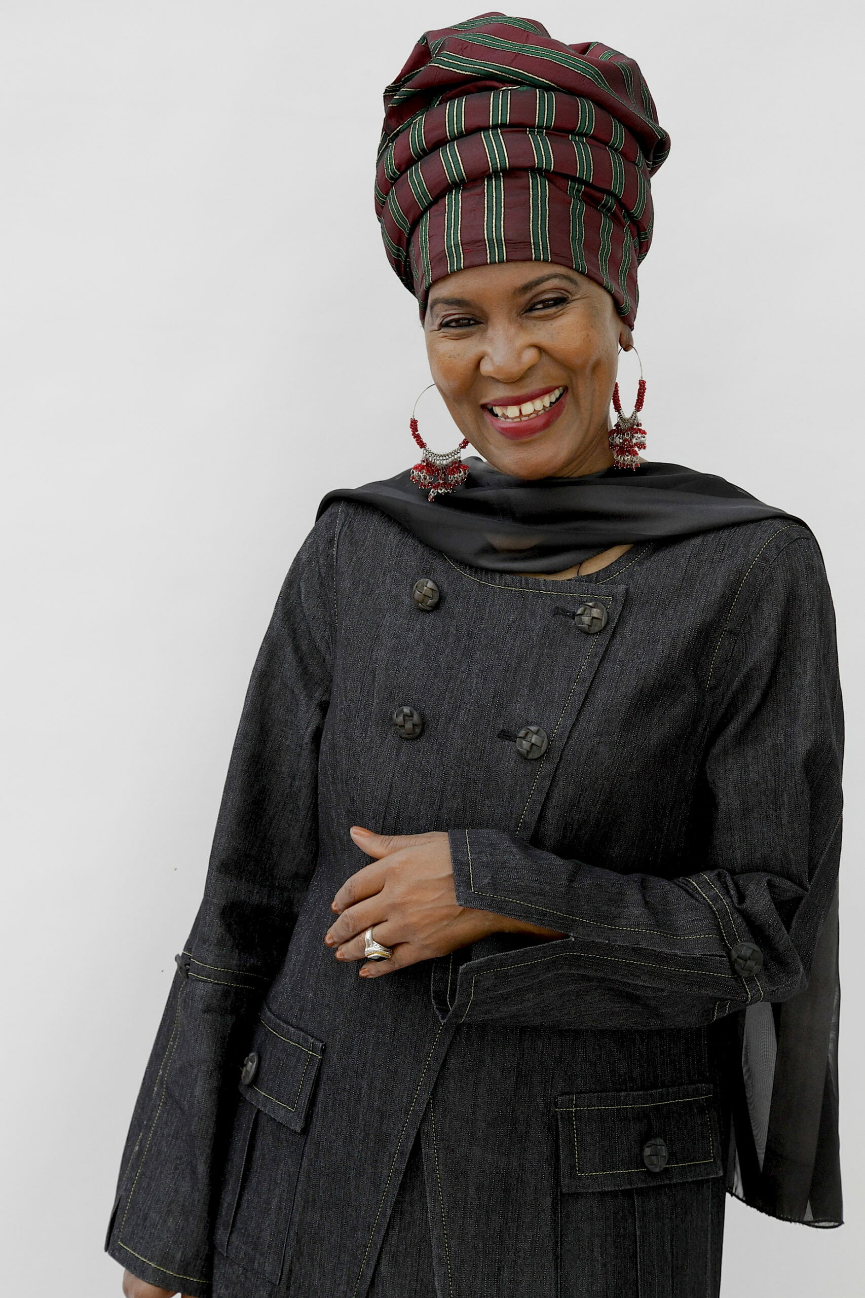 Ashro Woman of the Week, Wajeedah, a smiling black woman in a gray print headwrap and gray buttoned coat.