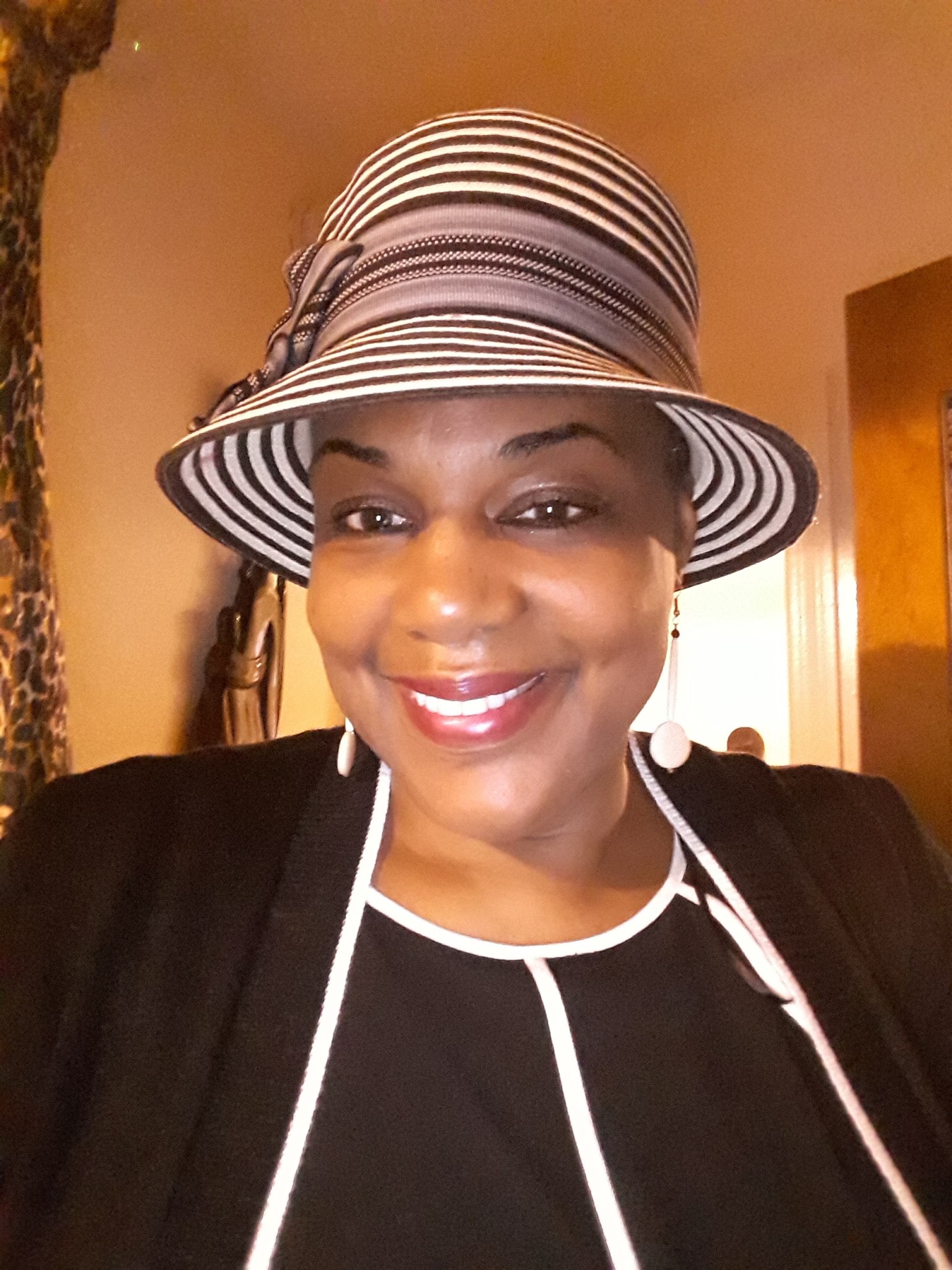 Ashro Woman of the Week MICHELLE B., wearing a black jacket dress with white trim and a summery hat.