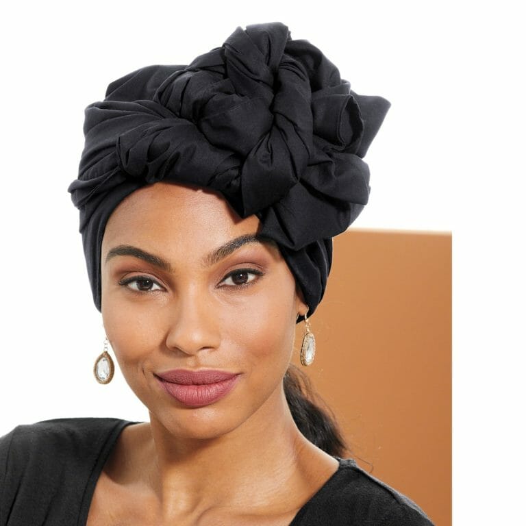 An African-American woman wearing a black headwrap, hoop earrings, and a black dress.