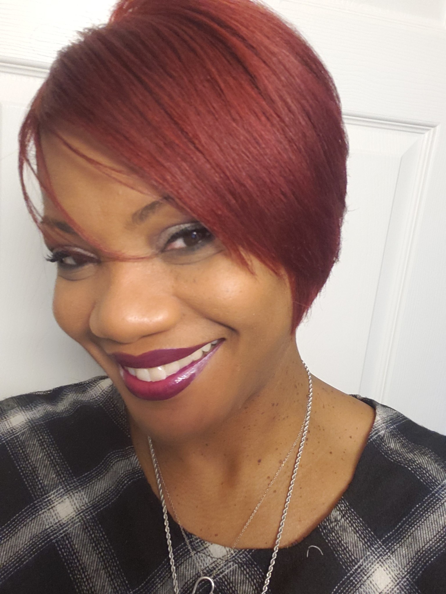 Ashro Woman of the Week Karen a smiling African-American woman wearing a black plaid blouse and has red hair.