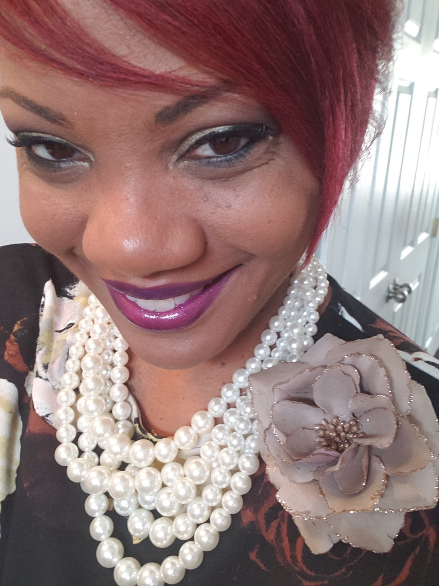 Ashro Woman of the Week Karen a smiling African-American woman wearing a black blouse, a pearl necklace, and has red hair.
