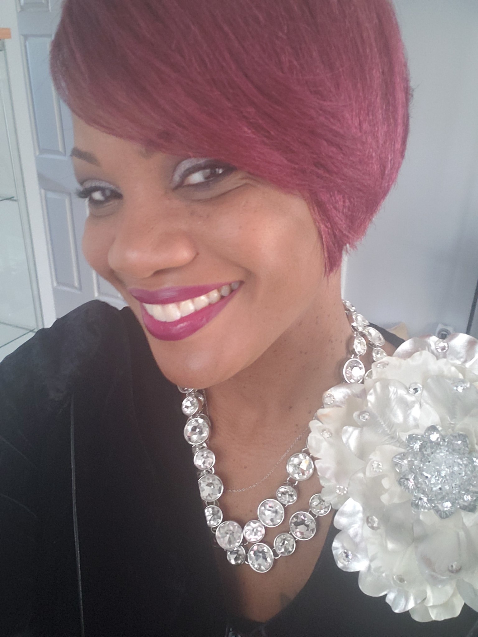 Ashro Woman of the Week Karen a smiling African-American woman wearing a black blouse with a white flower, a necklace, and has red hair.