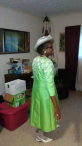 Ashro Woman of the Week Ruth, a smiling African-American woman wearing a green dress and hat.