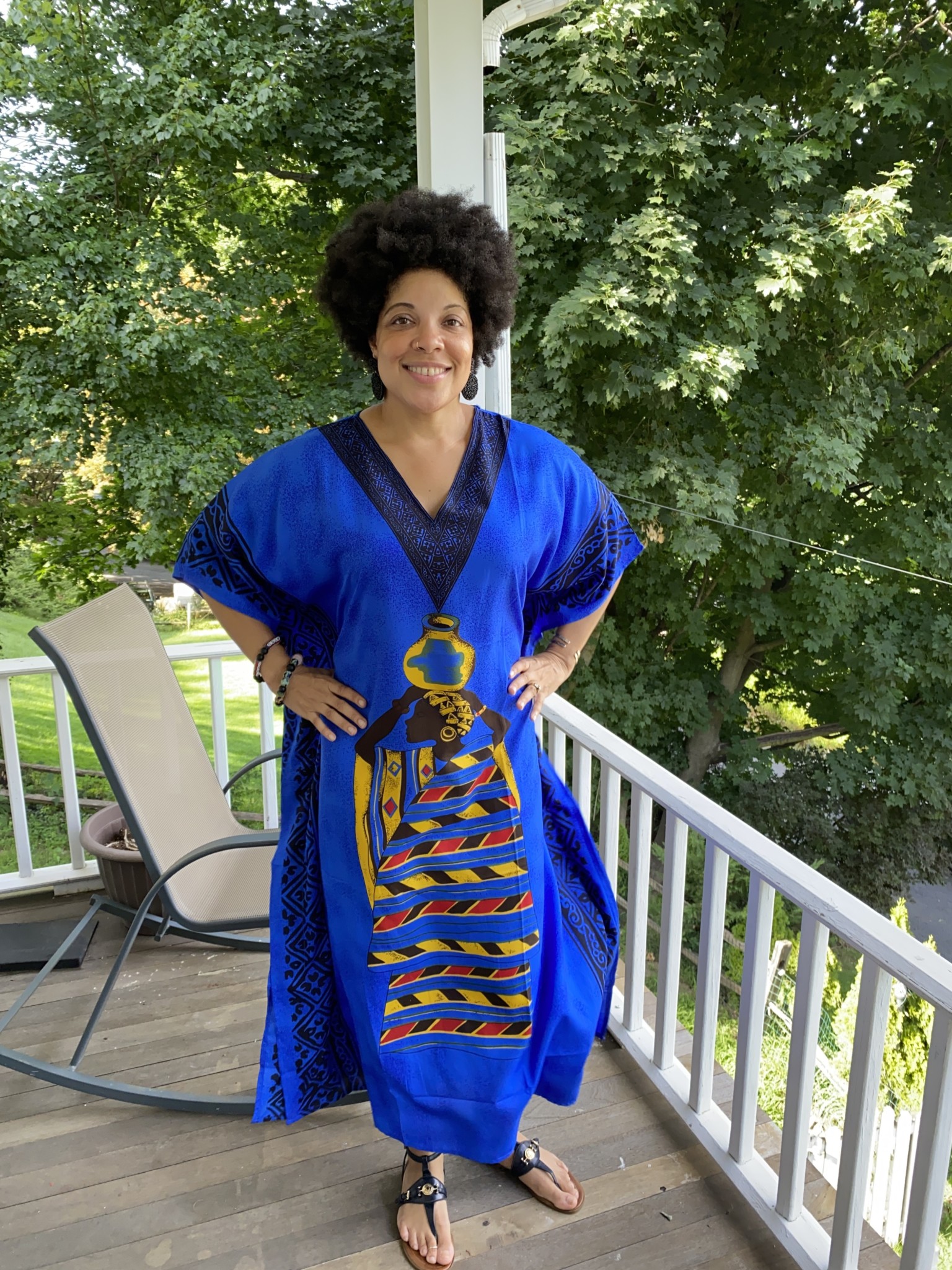 A black woman wearing a blue and Afrocentric patterned caftan.
